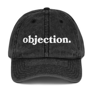May include: A black vintage washed cotton baseball cap with the word "objection." embroidered in white on the front.