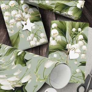 May include: Green and white floral wrapping paper with a lily of the valley pattern. The paper is rolled up and tied with twine. There is a white star and a white heart on the paper.