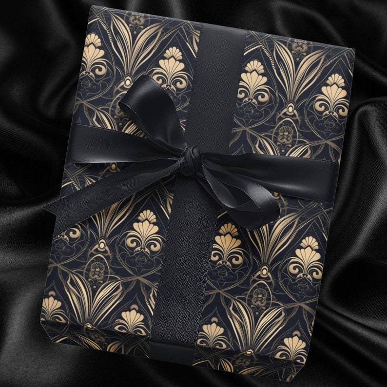Puede incluir: Una caja de regalo negra con un dise&ntilde;o estampado en oro y negro. La caja est&aacute; atada con una cinta negra.