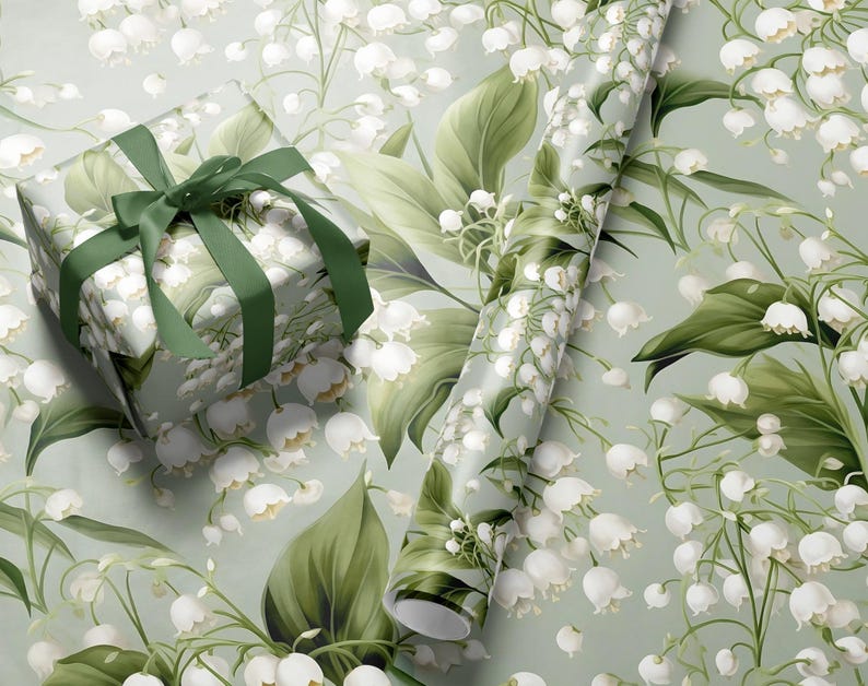 May include: A green and white gift wrap with a floral pattern of lily of the valley flowers. The gift wrap is wrapped around a gift box with a green ribbon.