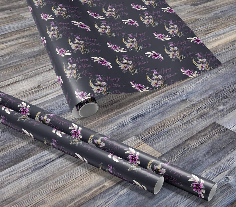 Puede incluir: Dos rollos de papel de regalo gris oscuro con un patr&oacute;n floral y el texto "Feliz D&iacute;a de la Madre" repetido en toda la superficie.