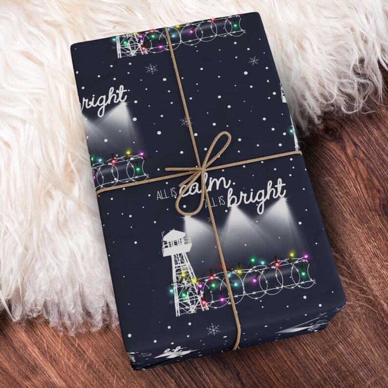 Pode incluir: Papel de embrulho azul com uma torre branca, luzes de corda e o texto "All is calm, all is bright".