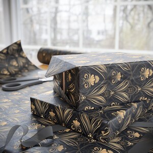 Puede incluir: Un rollo de papel de regalo negro y dorado con un patr&oacute;n decorativo. El papel presenta un dise&ntilde;o repetitivo de flores y hojas estilizadas.