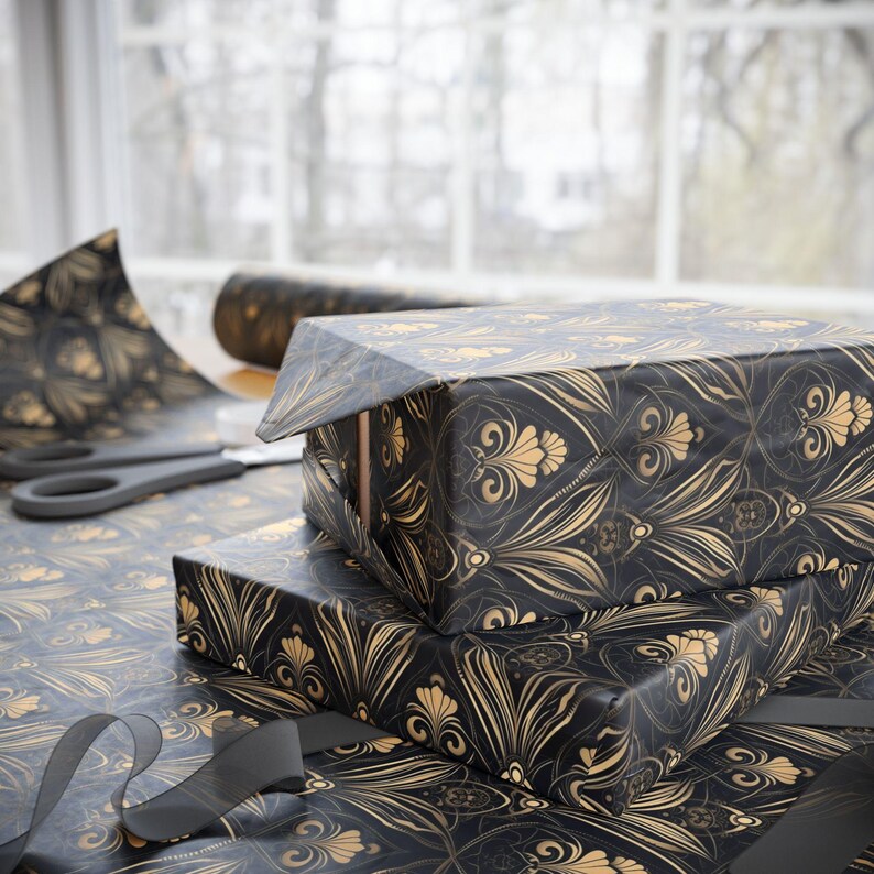 Puede incluir: Un rollo de papel de regalo negro y dorado con un patr&oacute;n decorativo. El papel presenta un dise&ntilde;o repetitivo de flores y hojas estilizadas.