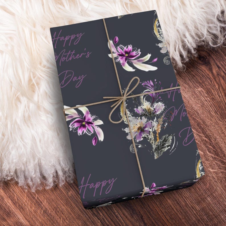 Puede incluir: Un papel de regalo azul oscuro con un patr&oacute;n floral y el texto "Happy Mother's Day" en morado. El papel est&aacute; atado con cuerda.