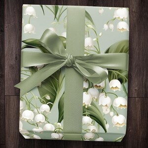 May include: A green gift box with a white and green floral pattern. The box is tied with a green satin ribbon.