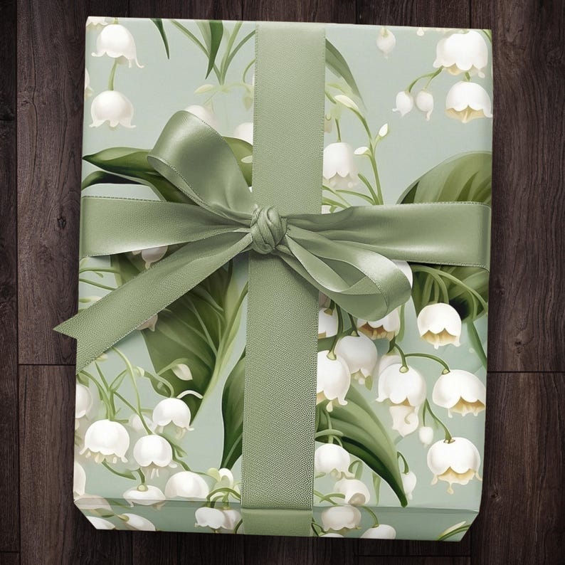 May include: A green gift box with a white and green floral pattern. The box is tied with a green satin ribbon.