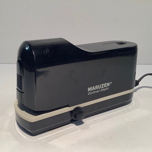 May include: A black electric stapler with a white trim and the text "MARUZEN® Electronic Stapler" on the front.