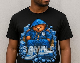 May include: Black t-shirt featuring a graphic of a teddy bear in a blue tracksuit and sneakers, surrounded by blue diamonds. The bear is wearing a blue hoodie with the text "CITY LIFE". The word "SAMPLE" is printed on the shirt.