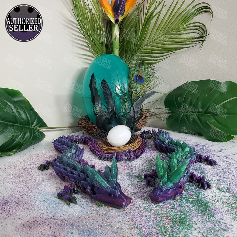 May include: A teal egg with black feathers, a white egg in a nest, and two purple and green crystal dragons. The image also includes a bird of paradise flower and the text "AUTHORIZED SELLER".