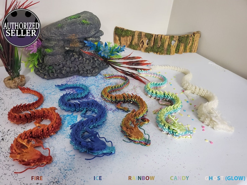 May include: A collection of colorful, articulated dragon figurines in various colors: fire, ice, rainbow, candy, and ghost (glow). The dragons are displayed on a white surface with decorative elements. The text "AUTHORIZED SELLER" is in a circular badge.