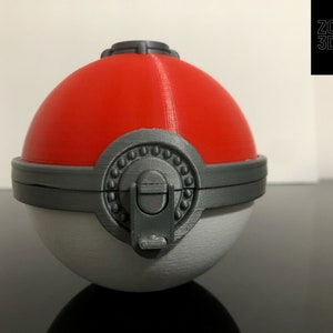 K&ouml;nnte beinhalten: Ein 3D-gedruckter Pok&eacute;ball mit roter Oberseite, wei&szlig;er Unterseite und einem grauen Verschluss. Der Pok&eacute;ball hat einen grauen Ring um die Mitte mit einer Reihe kleiner grauer Kreise.