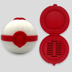 K&ouml;nnte beinhalten: Ein roter und wei&szlig;er Beh&auml;lter im Pokeball-Stil mit einem Scharnierdeckel. Der Deckel hat eine Reihe kleiner L&ouml;cher in der Mitte.