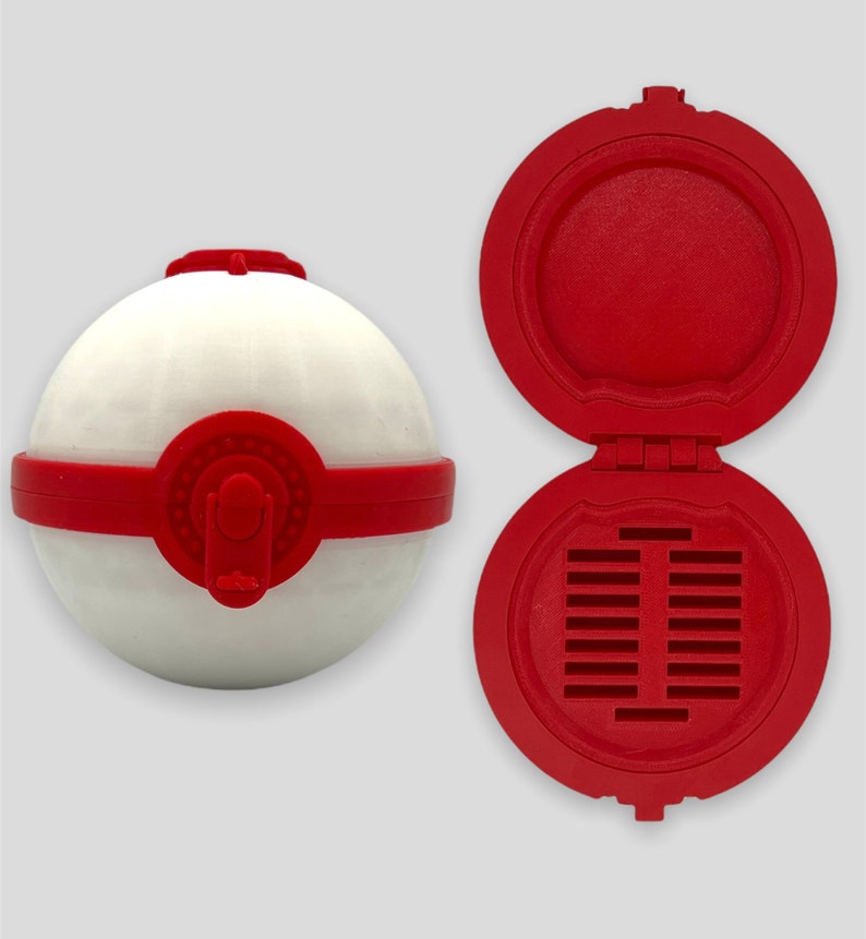 K&ouml;nnte beinhalten: Ein roter und wei&szlig;er Beh&auml;lter im Pokeball-Stil mit einem Scharnierdeckel. Der Deckel hat eine Reihe kleiner L&ouml;cher in der Mitte.
