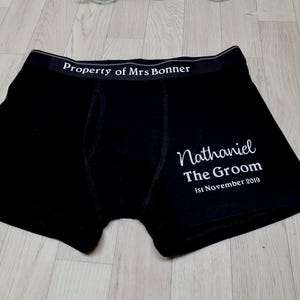May include: Black boxer shorts with white text. The waistband reads "Property of Mrs Bonner." The right leg has the text "Nathaniel The Groom 1st November 2019." A wedding gift.