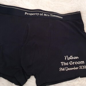 May include: Black boxer shorts with the text "Property of Mrs Timmins" printed on the waistband. The text "Nathan The Groom 31st December 2020" is printed on the leg of the underwear. The underwear is made of a soft material.