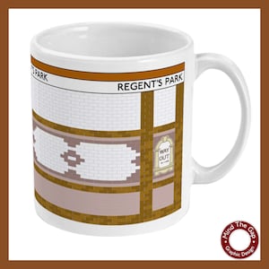 Puede incluir: Taza de cerámica blanca con un diseño marrón y blanco que representa la entrada de una estación de metro de Londres. El nombre de la estación "REGENT'S PARK" está impreso en texto negro en la taza. La taza también presenta un letrero "WAY OUT" con una flecha.