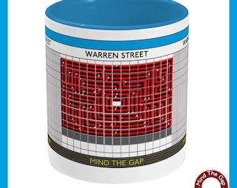 May include: White ceramic mug with a blue rim. The mug features a black and white graphic of a London Underground sign with the text "WARREN STREET" and a red maze pattern. The bottom of the mug has the text "MIND THE GAP" and a small logo that says "Mind The Gap Graphic Design".