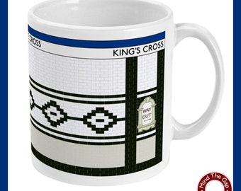 May include: White ceramic mug with a black and white graphic of a London Underground station entrance. The graphic includes the text "KING'S CROSS" and a sign that reads "WAY OUT".