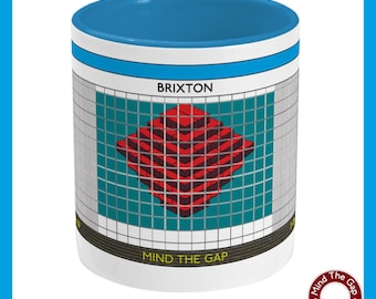 May include: White ceramic mug with a blue rim and a graphic of a red and black geometric design on a teal background. The graphic is surrounded by a white border and the text "BRIXTON" and "MIND THE GAP" are printed in black. The mug also features a small logo with the text "Mind The Gap Graphic Design" in a circle.