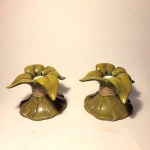 Un par de candelabros con hojas en forma de manojo