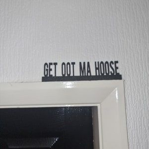 May include: A white door frame with a black sign above it that reads "GET OOT MA HOOSE".