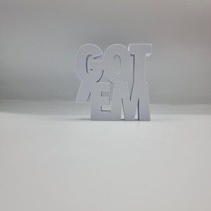 May include: White wooden block letters spelling out "GOT 'EM" on a white background.