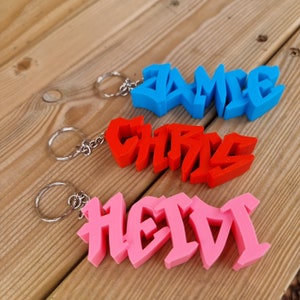 Porte-clés style graffiti | Étiquettes pour sac à dos, Porte-clés imprimés en 3D, Étiquettes pour enfant, Porte-clés graffiti, Pendentifs, Noms de sac d'école