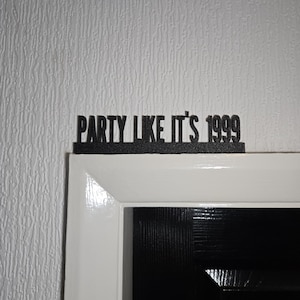 Puede incluir: Marco de puerta negro con un letrero negro que dice "Party Like It's 1999" sobre la puerta.