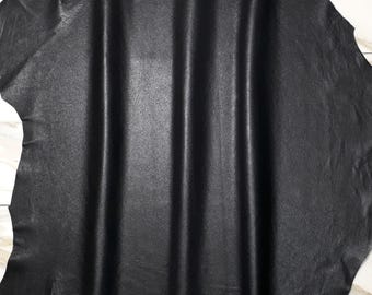 May include: Black leather hide with a smooth, slightly textured surface. The leather is folded in a way that shows the texture and sheen.