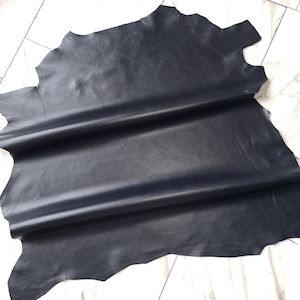 Könnte beinhalten: Ein Stück schwarzes Leder, dreimal gefaltet, mit einer glatten, glänzenden Oberfläche.