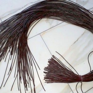 Puede incluir: Un paquete de cordones de cuero marrón, aproximadamente 100 piezas, atados juntos en un extremo.