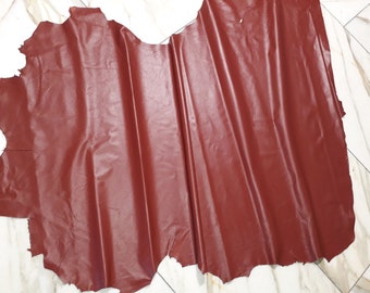 May include: A large piece of red leather with a smooth, slightly shiny surface. The leather is folded and has a slightly irregular edge.