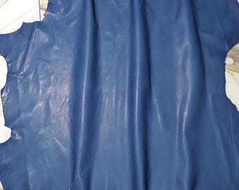 May include: A piece of blue leather with a smooth, slightly shiny finish. The leather is folded and draped over a white surface.