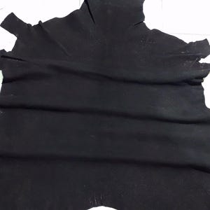 May include: A black leather hide with a textured surface. The hide is folded and has a few small holes.