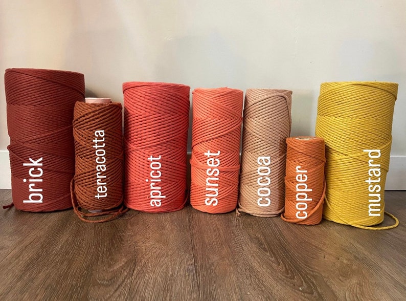 May include: Eight spools of cotton rope in various shades of red, orange, brown, and yellow. The spools are labeled with the color names: brick, terracotta, apricot, sunset, cocoa, copper, and mustard.