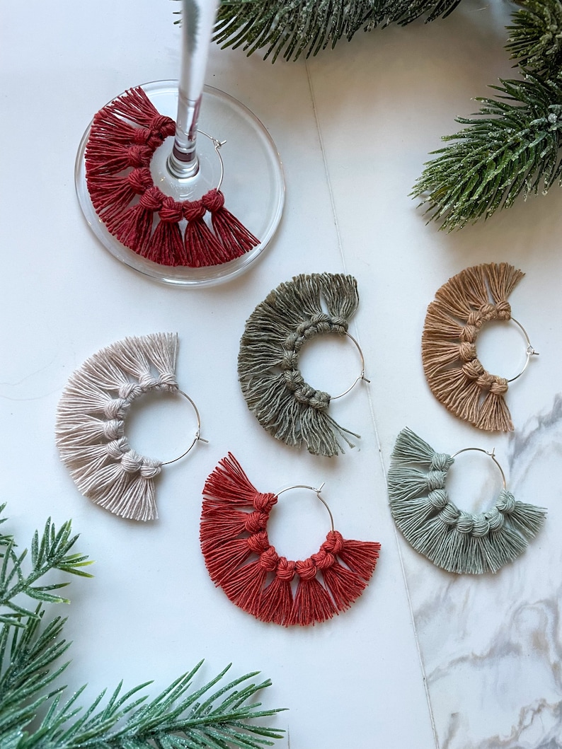 May include: Six pairs of hoop earrings with a fringe of tassels. The earrings are in various colors, including red, green, beige, and gray.