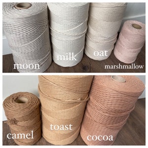 May include: Six spools of natural fiber rope in various shades of beige, brown, and pink. The spools are labeled with the names "moon", "milk", "oat", "marshmallow", "toast", and "cocoa".