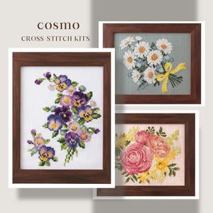 Könnte beinhalten: Drei gerahmte Kreuzstich-Sets mit floralen Designs. Der obere linke Rahmen zeigt einen Halbmond aus lila und gelben Stiefmütterchen. Der obere rechte Rahmen zeigt einen Strauß weißer Gänseblümchen mit gelbem Band. Der untere Rahmen hat rosa und gelbe Rosen.
