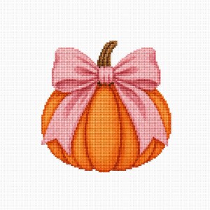 Puede incluir: Un patrón de punto de cruz de una calabaza naranja con un tallo marrón, que presenta un gran lazo de cinta rosa claro atado en la parte superior. El diseño está representado en un estilo de puntada de cuadrícula sobre un fondo blanco.