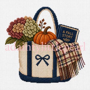 Könnte beinhalten: Ein Kreuzstichmuster mit einer cremefarbenen Tragetasche mit dunkelblauen Riemen und einem Schleifensymbol. Die Tasche enthält einen leuchtend orangefarbenen Kürbis, rote und grüne Hortensien, einen karierten Schal mit Fransen und ein blaues Buch A FALL STORY.
