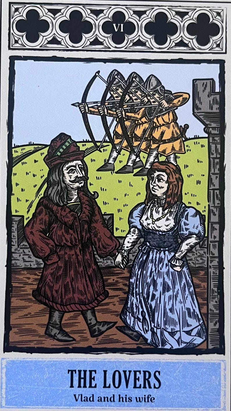 May include: A tarot card illustration depicting a couple standing together. The man is wearing a brown coat and a green hat. The woman is wearing a blue dress and a white necklace. The card is titled "THE LOVERS" with the text "Vlad and his wife" below. The card is surrounded by a black and white border.