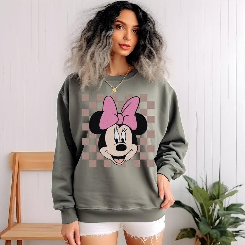 May include: A green sweatshirt with a checkered pattern and a cartoon image of Minnie Mouse with a pink bow.
