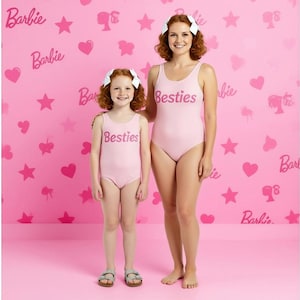 May include: Two people wearing matching light pink swimsuits with the word "Besties" printed on the front. The background is pink with "Barbie" text and heart and star shapes.