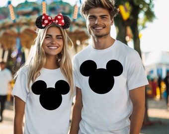 May include: A couple wearing white t-shirts with black Mickey Mouse silhouettes. The woman is wearing a red and white polka dot bow headband.