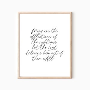 Op de afbeelding: Een ingelijste print met de tekst "Many are the afflictions of the righteous but the Lord delivers him out of them All" in elegant zwart schrift. De lijst is licht van hout, de achtergrond is wit.