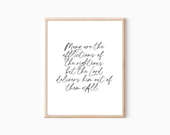 May include: A framed print with the text "Many are the afflictions of the righteous but the Lord delivers him out of them All" in elegant black script. The frame is a light wood color, and the background is white.
