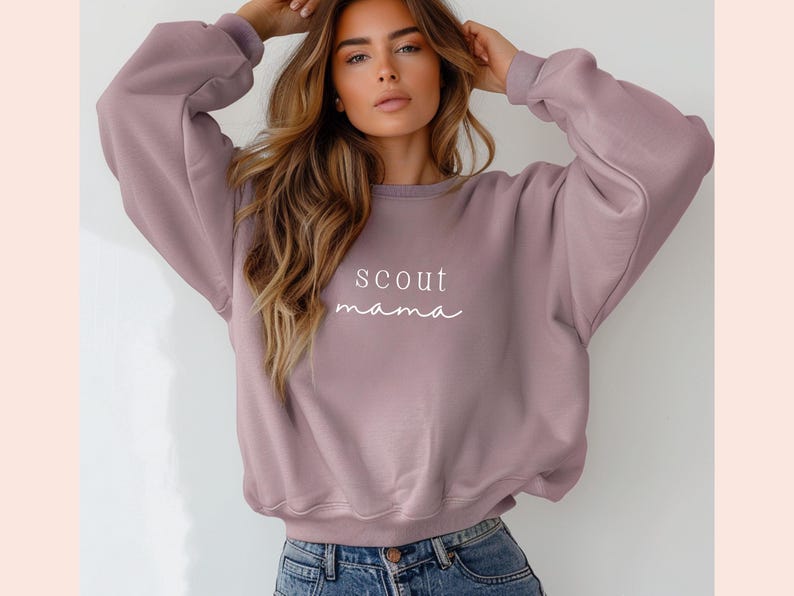 Puede incluir: Una sudadera de color malva con el texto "scout mama" impreso en blanco en la parte delantera.