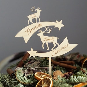 May include: Wooden Christmas tree topper featuring two reindeer silhouettes and the text "The Brown Family Christmas".