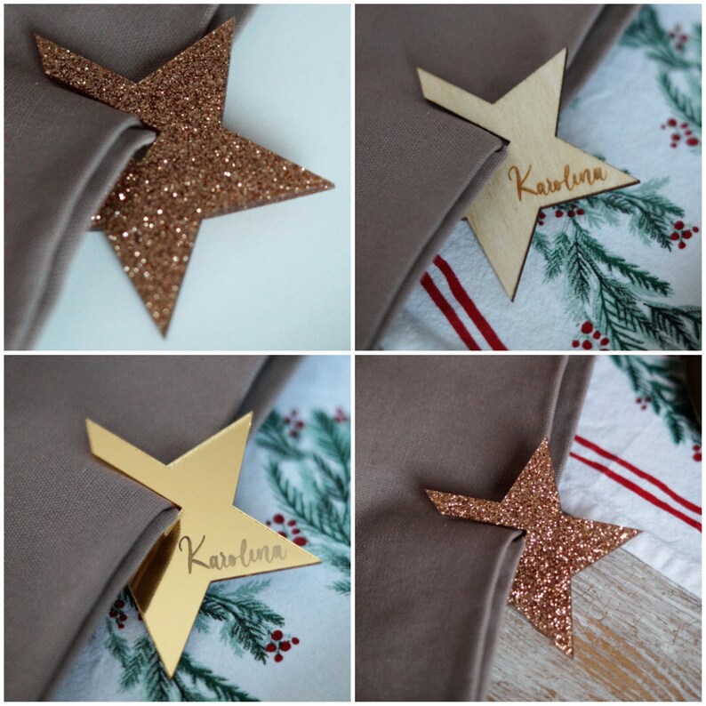 May include: Four place cards in the shape of a star, two are gold glitter, one is gold and one is wood. The wood place card has the name "Karolina" written on it.